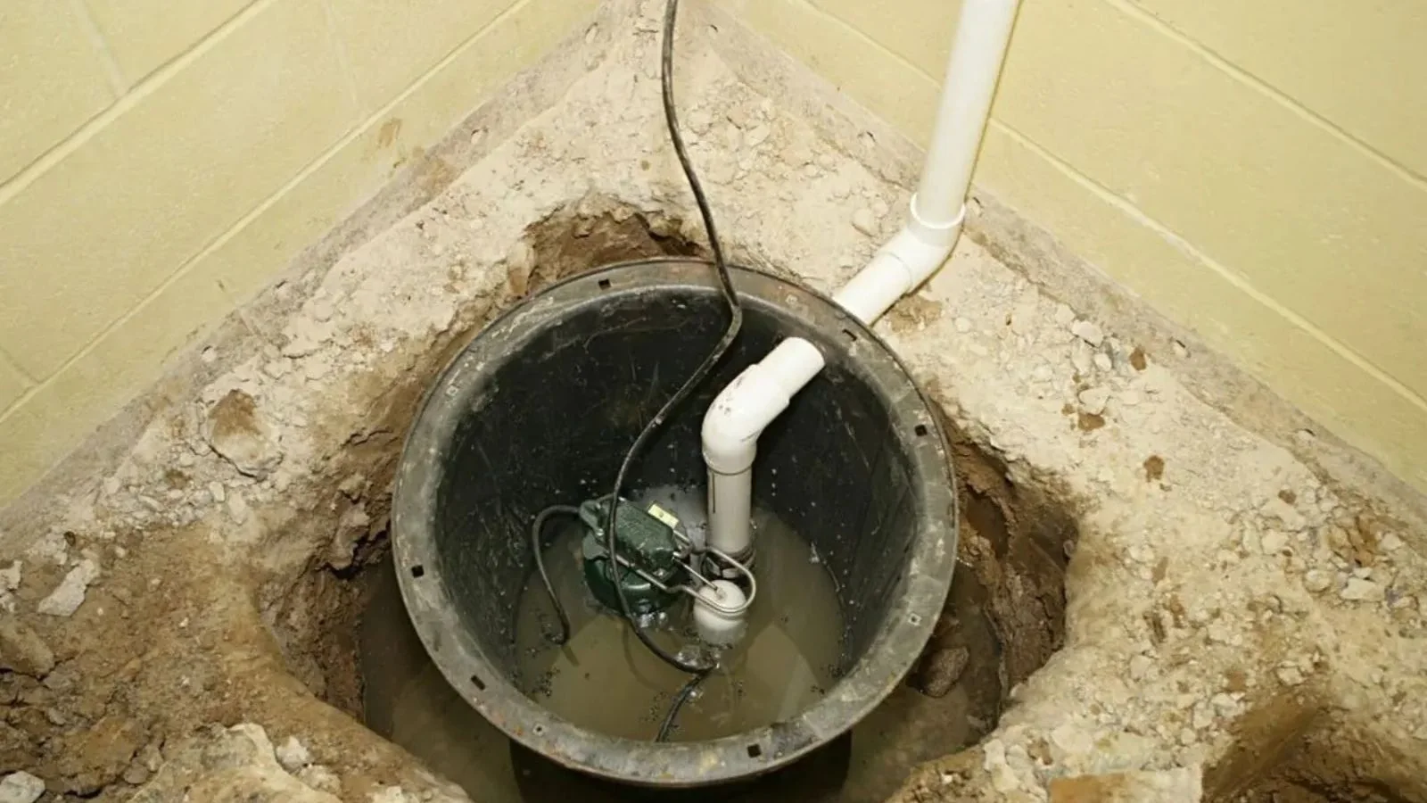 Sump pit with a pump and discharge pipe in a basement floor