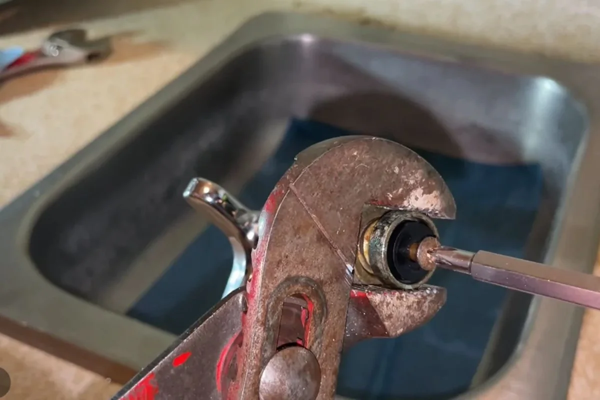 Pipe wrench on a faucet fitting in a stainless steel sink