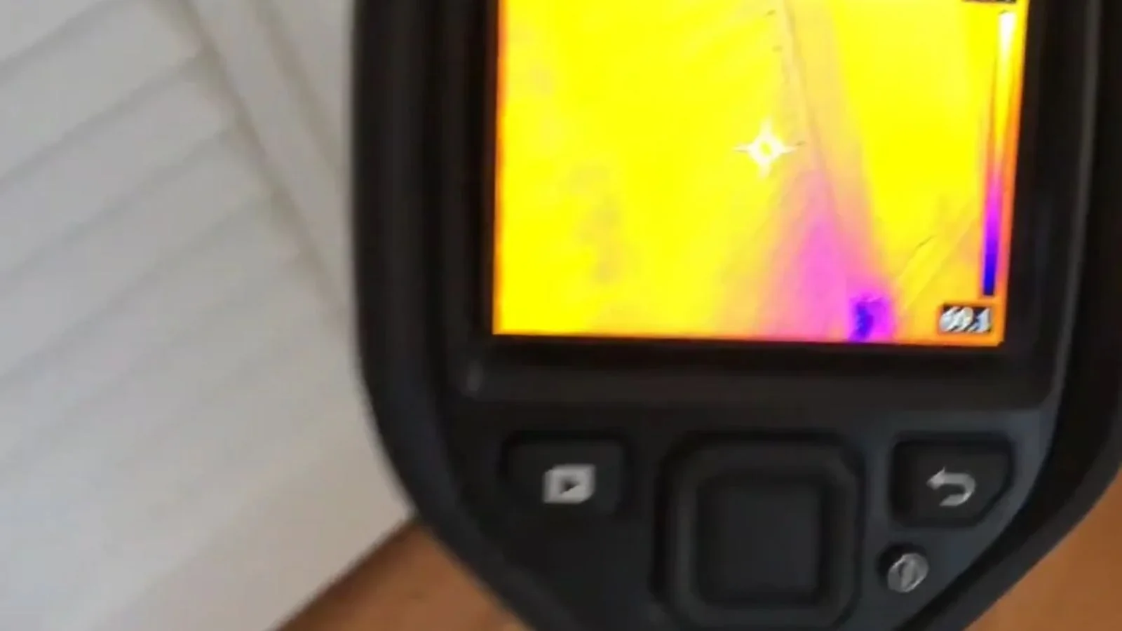 Thermal imaging camera screen showing a heat pattern on a wall