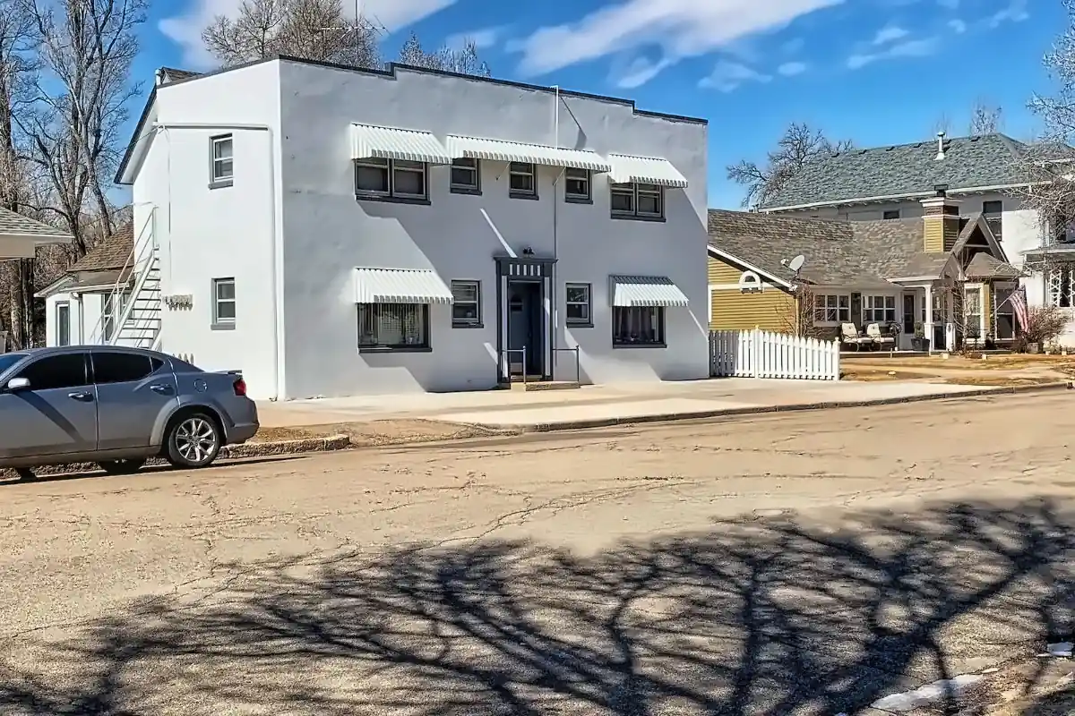 White two-story building with striped awnings on a quiet residential street in Eaton, Colorado