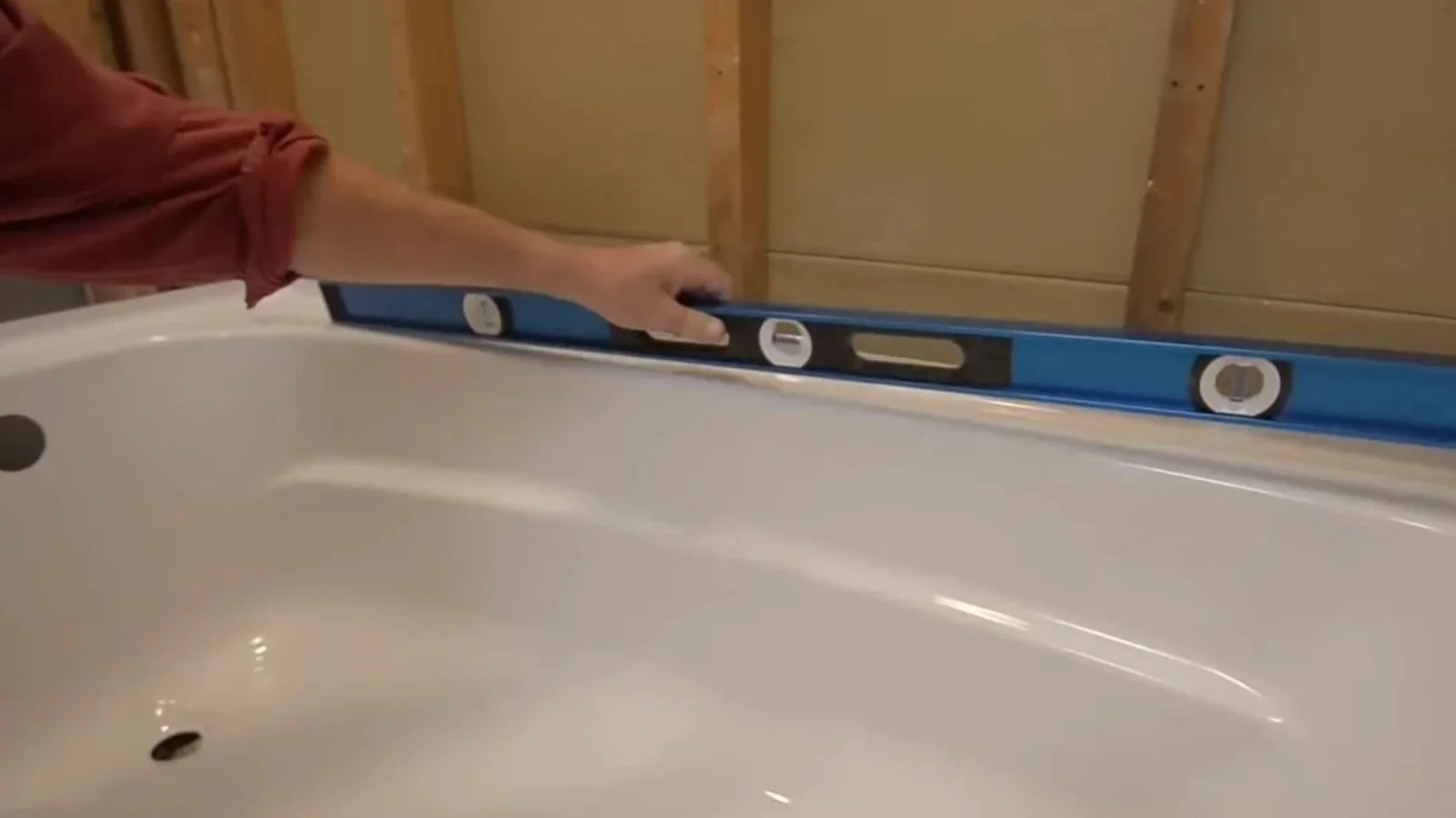 Level resting on the rim of a bathtub in an open framed alcove