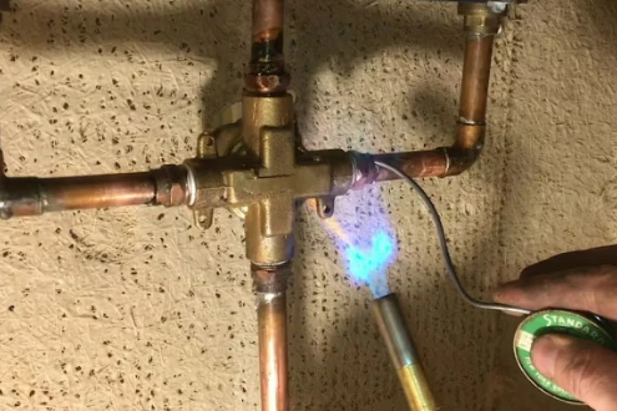 Torch flame heating copper fittings on a shower valve