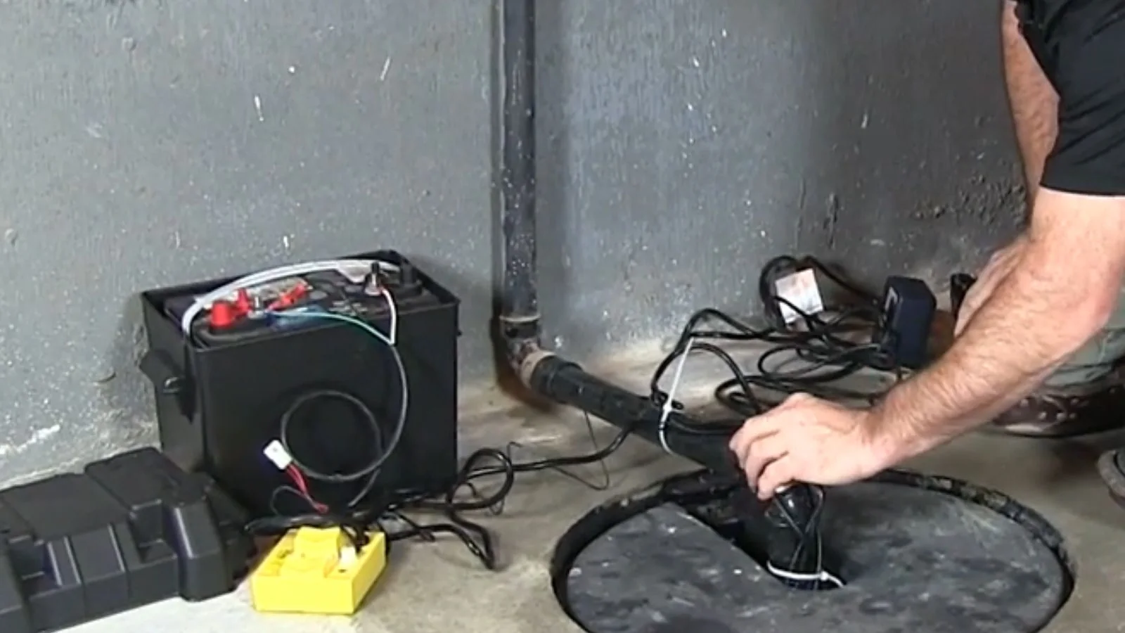 Technician connecting a battery backup system beside a sump pit