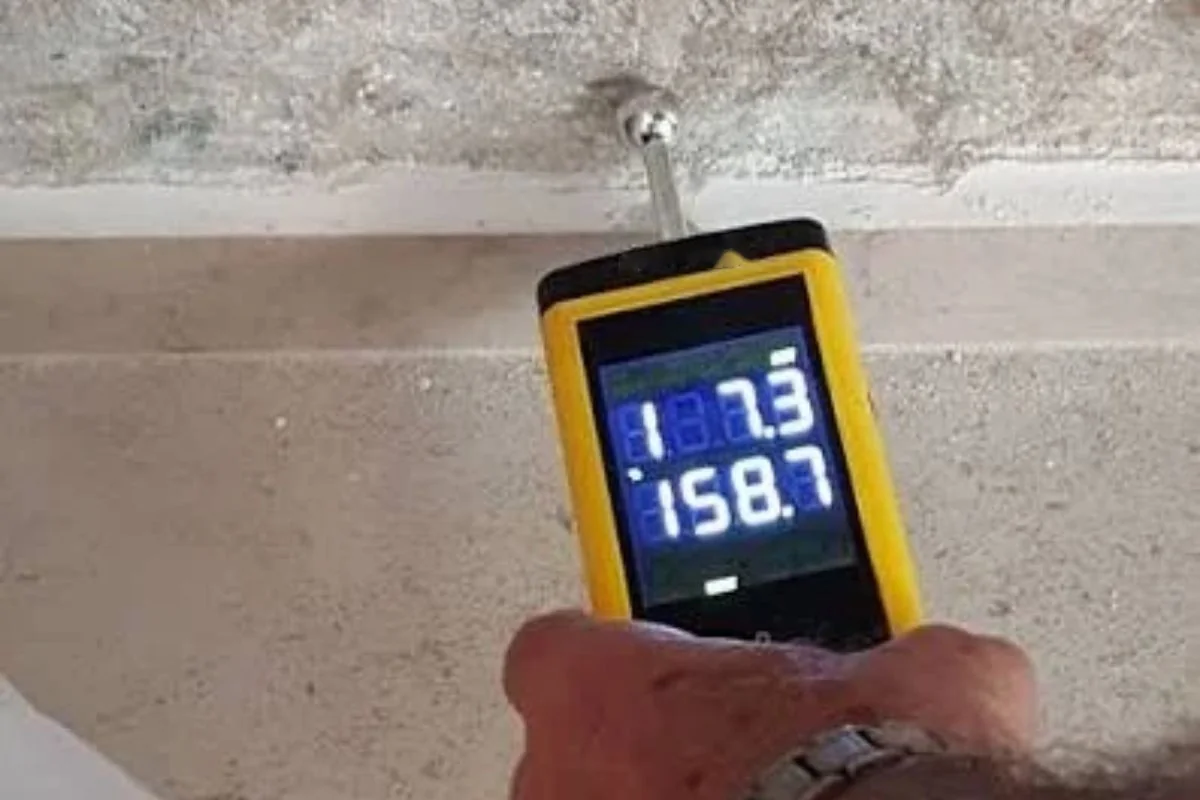Hand-held moisture meter pressed against a concrete wall