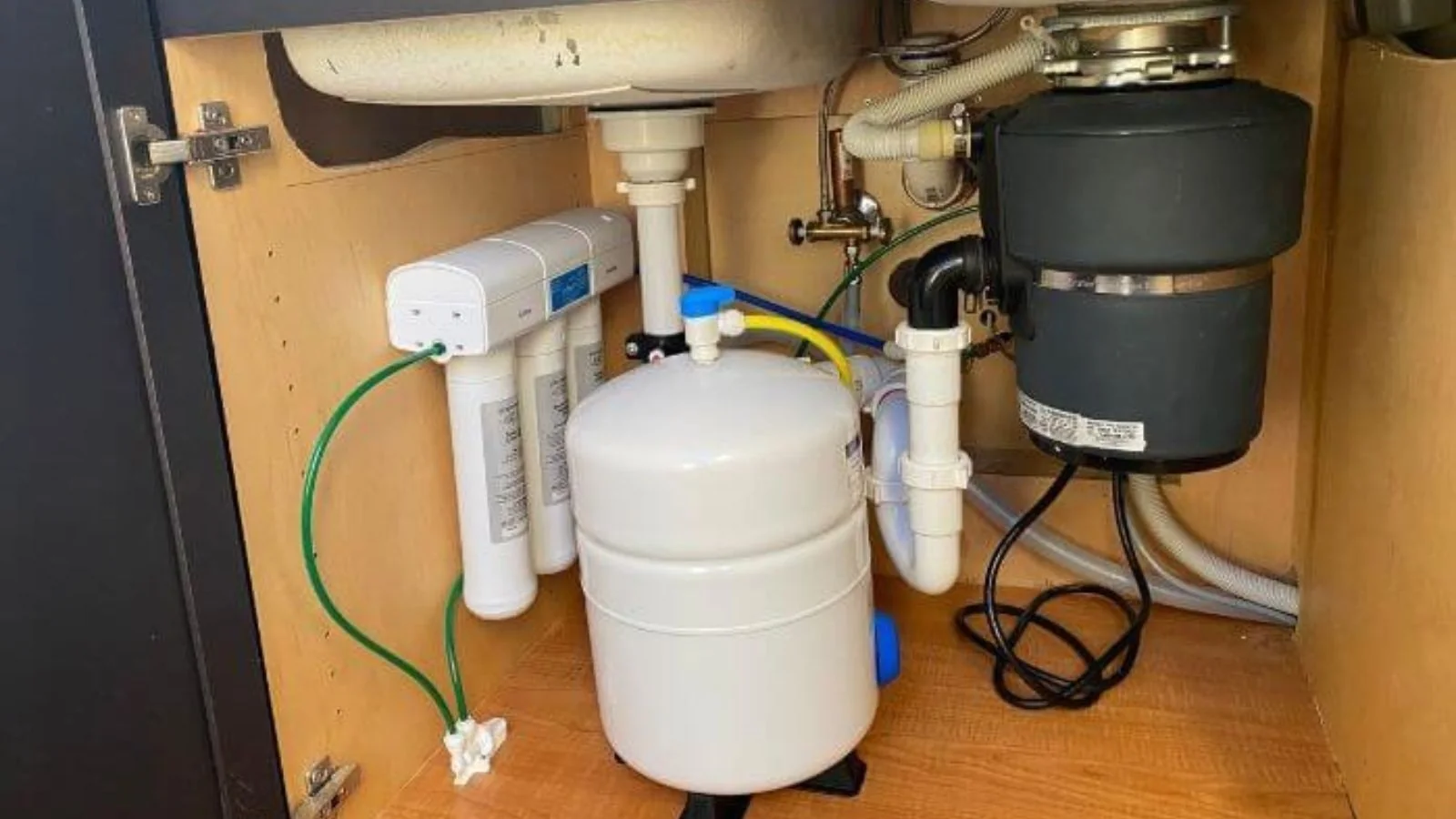 Under-sink reverse osmosis filter system with a storage tank beside a garbage disposal