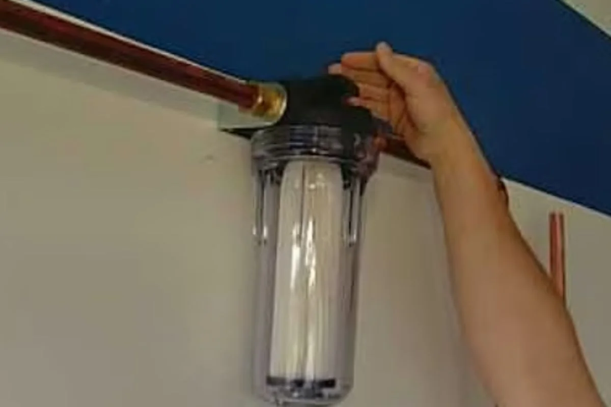 Hand fitting a clear whole-house filter housing onto a water line